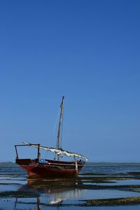 Boats in calm sea against clear sky