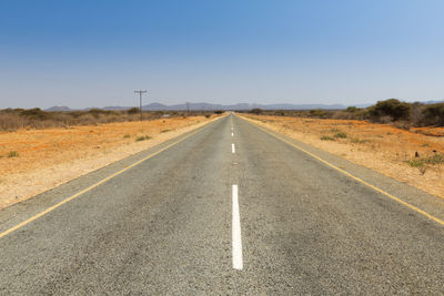 Road passing through land against clear sky