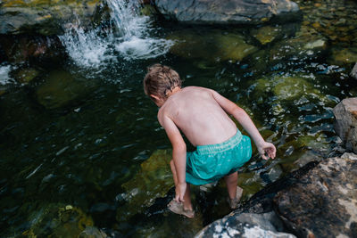 High angle view of boy looking into water