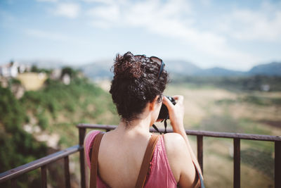 Rear view of woman photographing against sky