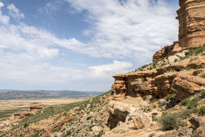 Rock formations on landscape against cloudy sky