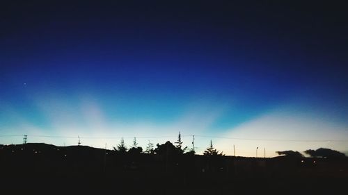 Silhouette trees against blue sky