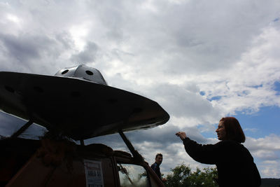 Low angle view of woman looking up against sky