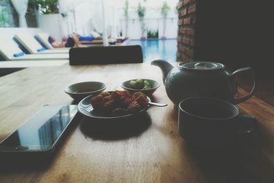 Food and drink with mobile phone on table against man relaxing in background