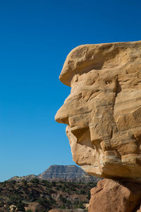 Low angle view of rock formations against clear blue sky