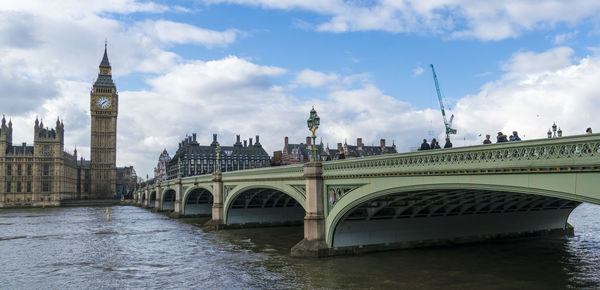 Arch bridge over river in city against sky