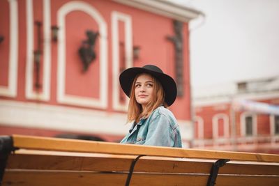 Portrait of smiling young woman standing against building