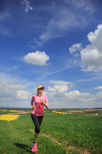 Full length of woman running on land against sky