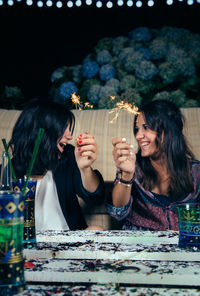 Young friends holding sparkler during party in backyard at night