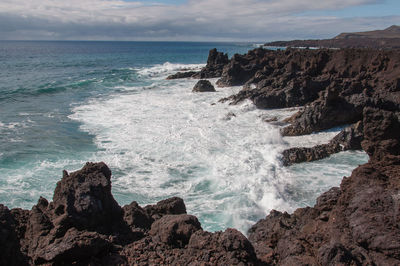 Scenic view of rocks in sea against sky