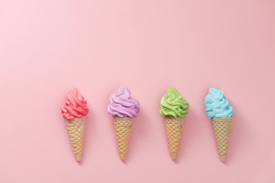 Various of colourful meringue ice cream cone on pink background