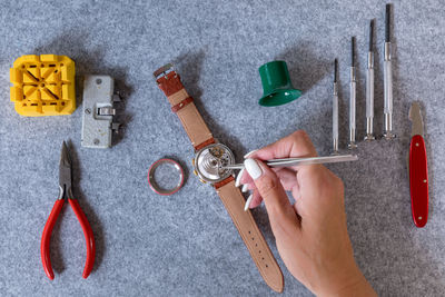 Cropped hand of woman repairing wristwatch on table