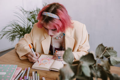 Young woman wearing blazer drawing on book