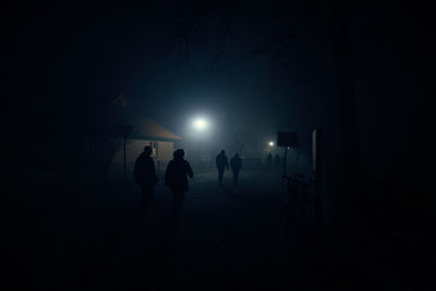 Silhouette people on illuminated street at night