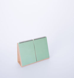 High angle view of blank green desk calendar against white background