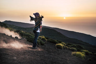 Man standing on mountain against sky during sunset