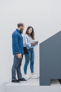 Male and female coworkers standing in creative office and discussing new business project together