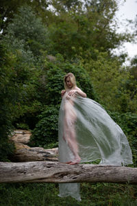 Woman standing by tree in forest