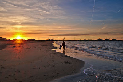 People on beach against sky during sunset