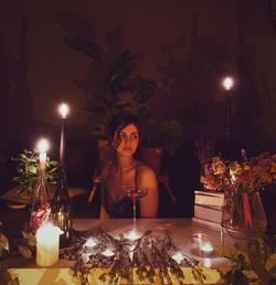 Portrait of young woman sitting by christmas tree at night