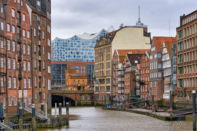 Buildings by canal against sky in city