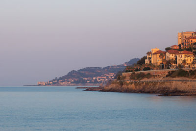 Scenic view of sea by buildings against clear sky