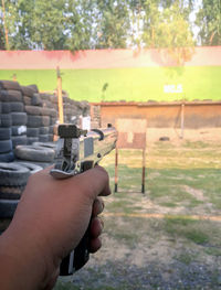 Close-up of hand aiming with gun outdoors