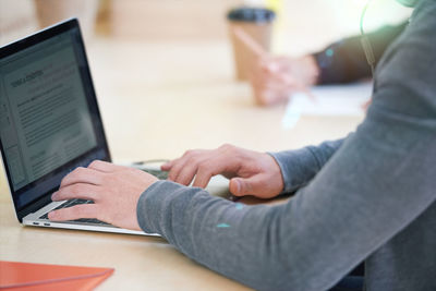 Midsection of woman using laptop at home