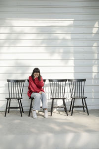 Asian teenager sitting on wood desk against white wall background