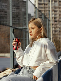 Midsection of woman holding camera while sitting outdoors