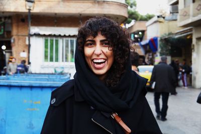 Portrait of happy woman standing against buildings in city