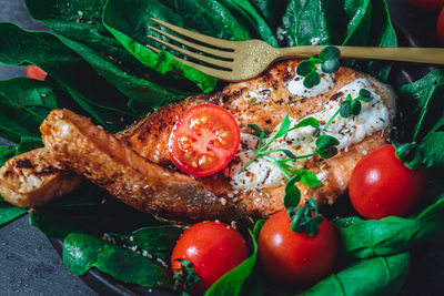 A plate with fresh green raw spinach and fried wild salmon, tomatoes and cream cheese sauce 