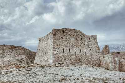 Low angle view of old ruin building against cloudy sky