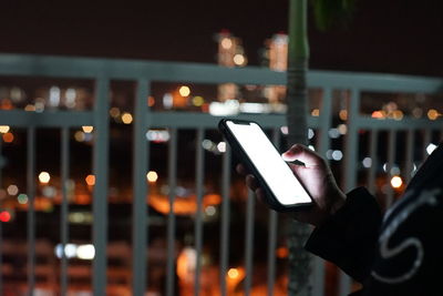 Close-up of hand using mobile phone at night