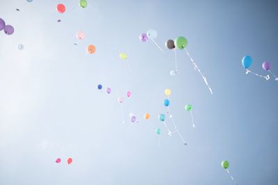 Low angle view of balloons flying against sky