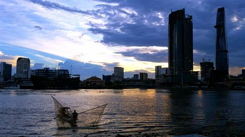 Silhouette man on boat fishing in river at sunset