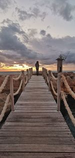 Rear view of person on pier at sunset