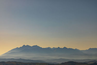 Scenic view of silhouette mountains against clear sky during sunset