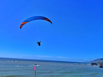 Paraglidier flying over sea against sky