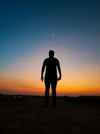 Silhouette man standing on land against sky during sunset