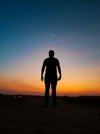 Silhouette man standing on field against sky during sunset