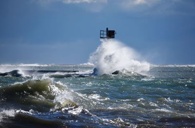 Waves breaking against sea against sky