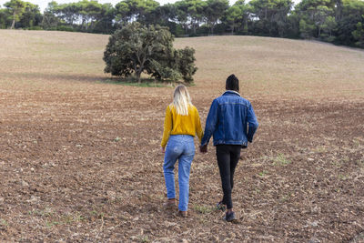 Young man holding hand of girlfriend and walking on field