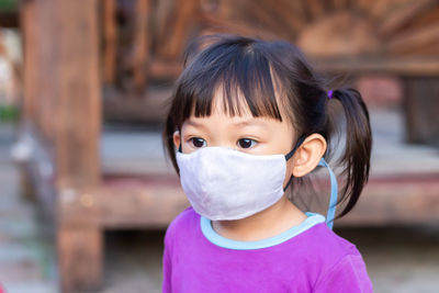 Close-up of girl wearing mask standing outdoors