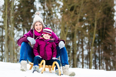 Women sitting on snow covered trees during winter