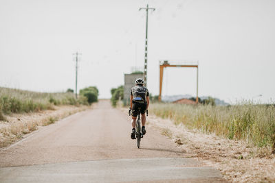 Rear view of man riding bicycle on road