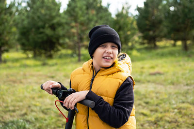 Boy rides an electric scooter in autumn park. schoolboy using e-scooter at sunny day.