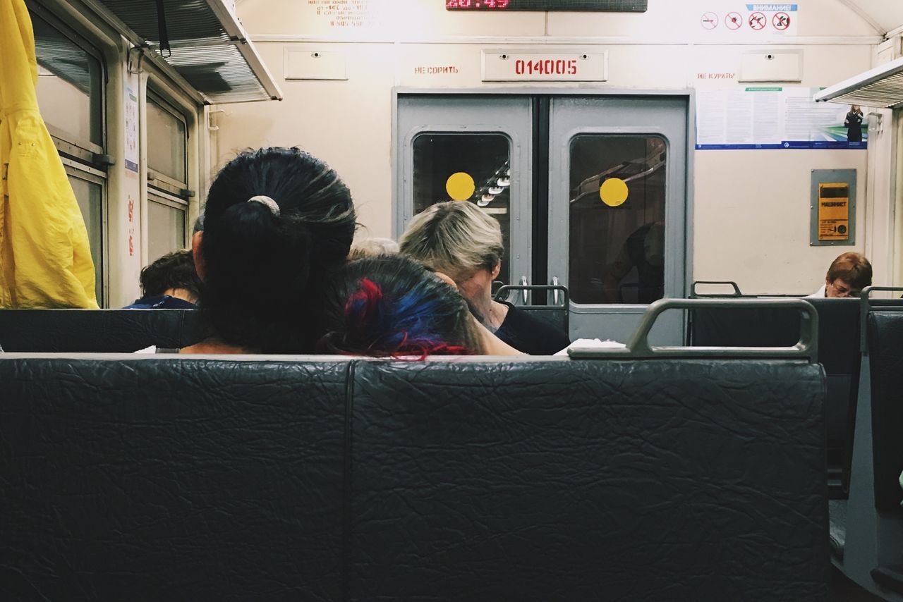 vehicle interior, transportation, real people, public transportation, indoors, train - vehicle, vehicle seat, sitting, mode of transport, passenger, rear view, lifestyles, women, headshot, technology, men, day, people