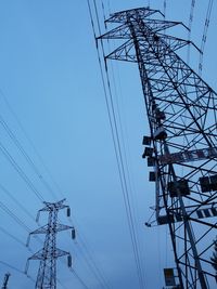 Low angle view of electricity pylon against clear blue sky