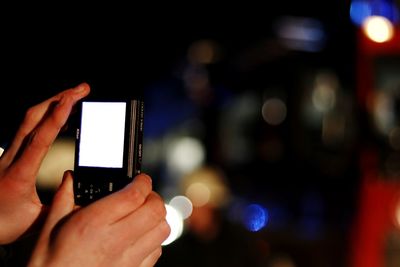 Close-up of hands photographing with camera at night